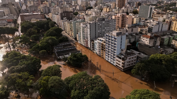 Aerial view of a city with white high-rise buildings flooded by brown floodwater.